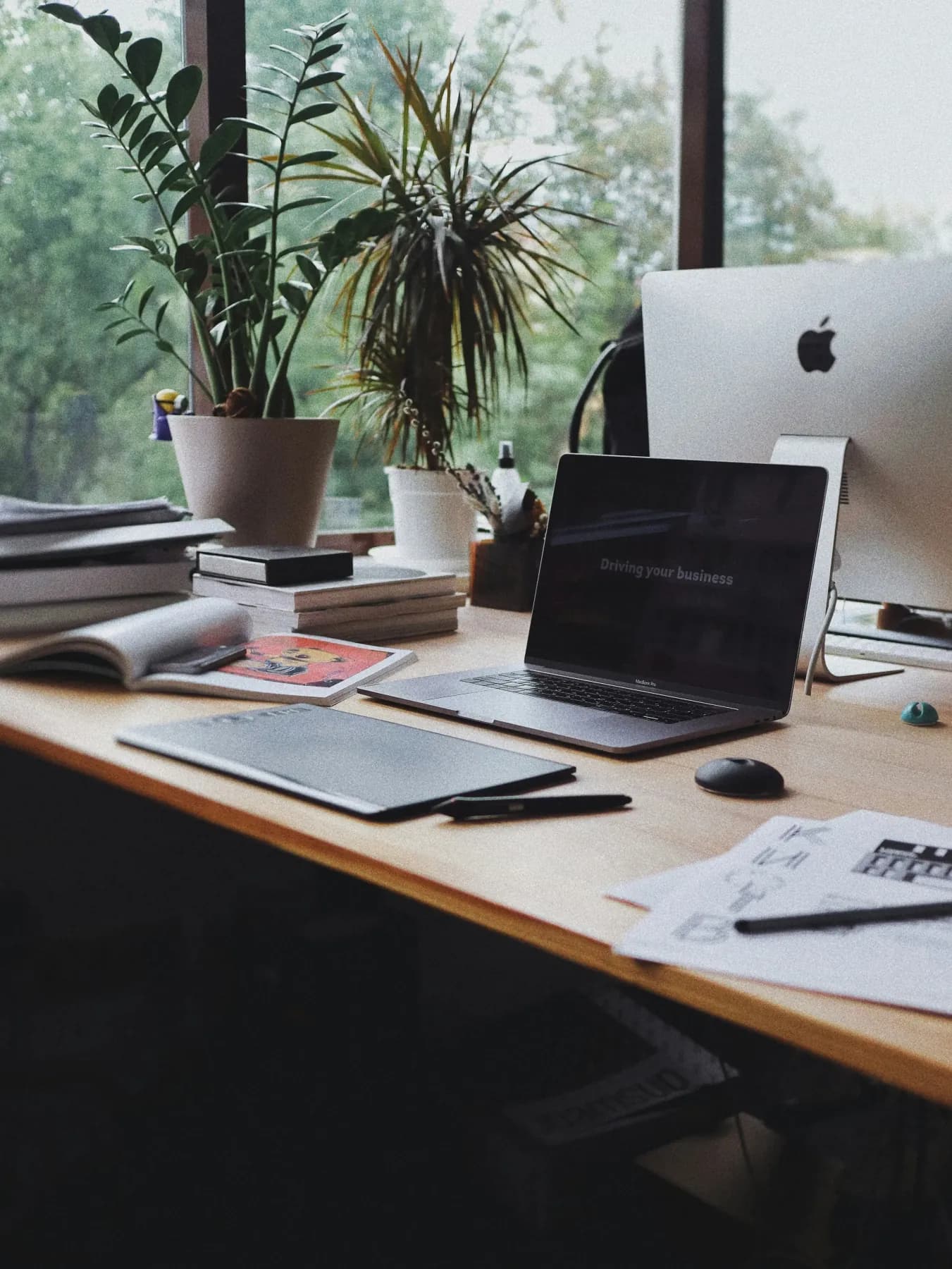 Bureau de travail avec ordinateurs, carnets et plantes